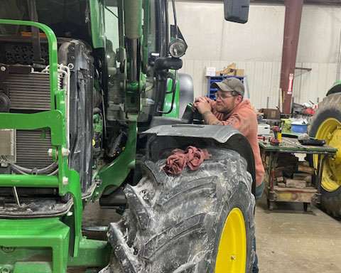 IMI Equipment LLC mechanic working on tractor